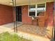 Inviting covered porch with brick surround, adorned with a stylish wicker chair and floral rug at 8990 N 850 W, Fairland, IN 46126