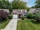Aerial view of a lovely home with a well-manicured front lawn, mature trees, and a driveway at 9700 River Oak E Ln, Fishers, IN 46038