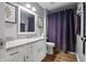 Well-lit bathroom features a granite-topped vanity, framed mirror, and shower with purple curtain at 9700 River Oak E Ln, Fishers, IN 46038