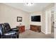 Spacious room displays a TV, armchair, side table with flowers, and neutral walls at 1056 Hilltop Commons Blvd, Whiteland, IN 46184