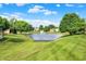 Scenic view of a pond with a fountain surrounded by lush green grass and mature trees at 1056 Hilltop Commons Blvd, Whiteland, IN 46184