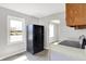 Galley kitchen with black refrigerator, updated flooring, and plentiful natural light, optimizing space for efficient meal preparation at 11 14Th St, Franklin, IN 46131