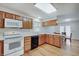 Bright kitchen featuring stainless sink, wood cabinetry, laminate flooring, and white appliances at 12515 Traverse Pl, Fishers, IN 46038