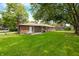 Spacious backyard featuring a well-maintained lawn and a brick house with mature trees at 3210 Flintwood Dr, Columbus, IN 47203
