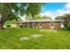 Backyard with lush green grass, mature trees, and a brick house at 3210 Flintwood Dr, Columbus, IN 47203