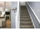 View of staircase that has grey carpeted steps and white railing, with a glimpse into the living room at 4442 Victory Cir, Indianapolis, IN 46203
