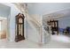 Elegant foyer featuring a wooden staircase, a grandfather clock, and an open view to the dining room at 4763 Woods Edge Dr, Zionsville, IN 46077