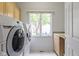 Bright laundry room with modern washer, dryer, cabinets, sink, and natural light at 4763 Woods Edge Dr, Zionsville, IN 46077