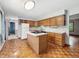 Well-lit kitchen featuring wood cabinets, an island cooktop, and a view into an adjacent room at 5240 Southdale Dr, Indianapolis, IN 46217