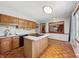 Eat-in kitchen featuring a center island with cooktop, wood cabinets, and view into an adjacent room at 5240 Southdale Dr, Indianapolis, IN 46217