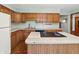 Up-close view of the kitchen, showcasing an island cooktop, wood cabinets, and neutral countertops at 5240 Southdale Dr, Indianapolis, IN 46217