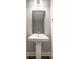 Small bathroom with a white pedestal sink, large mirror, and modern light fixture at 529 E Merrill St, Indianapolis, IN 46203