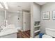 This primary bathroom features dual sinks, white marble countertops, white cabinets, a shower, and wood-look flooring at 5441 Ellsworth Dr, Plainfield, IN 46168