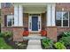 Inviting front porch showcasing brick pillars, a vibrant blue door, and charming flower-filled planters at 5441 Ellsworth Dr, Plainfield, IN 46168