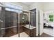 Walk-in shower features brown tiling, built-in bench, glass doors and an adjustable shower head at 5441 Ellsworth Dr, Plainfield, IN 46168