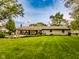 Back exterior view of home featuring a patio, manicured lawn, landscaping, and mature trees at 7405 N Janna Dr, Muncie, IN 47303