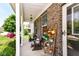 Inviting covered porch with brick siding, wood benches, colorful flower planters, and a ceiling fan at 7733 Chestnut Eagle Ct, Zionsville, IN 46077