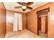 Bedroom with wood paneling, ceiling fan, and window with curtains, offering a cozy, retro aesthetic at 7829 Rahke Rd, Indianapolis, IN 46217