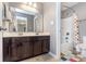 Well-lit bathroom featuring a double sink vanity, large mirror, and shower with colorful curtain at 8556 N Deer Hill Dr, McCordsville, IN 46055