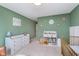 Cozy Bedroom featuring green walls, changing table, shelving unit with toys, and a golden crib at 8556 N Deer Hill Dr, McCordsville, IN 46055