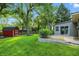 Lush backyard with mature trees, a red outbuilding, and a brick patio area at 8635 Bishops Ln, Indianapolis, IN 46217
