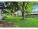 Spacious backyard featuring mature trees, lush greenery, and a charming red shed at 8635 Bishops Ln, Indianapolis, IN 46217