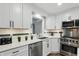 A kitchen sink area and a window overlooking the backyard are surrounded by white cabinetry and stainless appliances at 8635 Bishops Ln, Indianapolis, IN 46217
