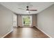 Neutral living room featuring hardwood floors, ceiling fan, large window, and entry to foyer with white door at 8635 Bishops Ln, Indianapolis, IN 46217