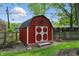 Charming red outbuilding with white trim, set against a backdrop of mature trees and greenery at 8635 Bishops Ln, Indianapolis, IN 46217