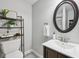 Well-lit bathroom featuring a gray wall, framed mirror, sleek vanity, and stylish decorative shelving at 9840 N Anchor Bnd, McCordsville, IN 46055
