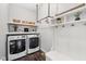Laundry room with white washer and dryer and white storage hooks and shelves at 9840 N Anchor Bnd, McCordsville, IN 46055