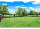 A large, green backyard featuring a picket fence and mature trees, offering privacy and space for outdoor activities at 10306 Mcclain Dr, Brownsburg, IN 46112