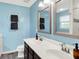 Bright bathroom with double sinks, decorative mirrors, and subway-tile shower with frameless glass doors at 10306 Mcclain Dr, Brownsburg, IN 46112