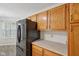 Close-up of kitchen with stainless steel fridge, wood cabinets, modern countertops and tile backsplash at 12207 Blue Sky Dr, Fishers, IN 46037