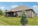 Expansive backyard showcasing the brick exterior, landscaping, and covered patio area at 1295 Maclaren Ct, Franklin, IN 46131