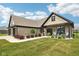 Charming brick home with well-kept lawn, inviting front porch with chairs, and lovely landscaping details at 1295 Maclaren Ct, Franklin, IN 46131