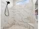 Close up of shower featuring white marble tile, built in shelves and bench seating, and window at 1295 Maclaren Ct, Franklin, IN 46131
