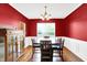 An elegant dining room featuring red walls, a decorative chandelier, and hardwood floors at 16138 Palmyra Green, Westfield, IN 46074