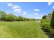 Lush green lawn and a pond feature in the backyard with mature landscaping and blue skies above at 16550 Gleneagles Ct, Noblesville, IN 46060