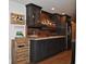 Stylish basement bar with rustic wood accents, granite countertop, and dark cabinetry at 16550 Gleneagles Ct, Noblesville, IN 46060