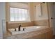 Bathroom featuring a tub with tile surround, window with blind, and a white towel on a rack at 16550 Gleneagles Ct, Noblesville, IN 46060
