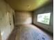 Empty bedroom with wood floors, patterned wallpaper, and a window overlooking the yard at 1739 E 18Th St, Anderson, IN 46016