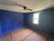 Bedroom features unfinished floors, blue paint, and a ceiling fan at 1739 E 18Th St, Anderson, IN 46016