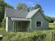 Quaint exterior view of a home with weathered siding and an overgrown yard under a blue sky at 1739 E 18Th St, Anderson, IN 46016