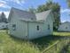 Rear view of a green house featuring siding, windows with white shutters, and overgrown lawn at 1739 E 18Th St, Anderson, IN 46016