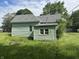 Rear view of home with green siding, a visible roof vent, and lush green yard at 1739 E 18Th St, Anderson, IN 46016