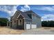 Side exterior of a new construction home highlighting the attached two-car garage and complementary stone and siding finishes at 1919 Delp Ct, Avon, IN 46123