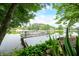 Scenic lake view featuring a boat dock and a pontoon boat, framed by verdant trees and a blue sky at 3695 Windsor Pl, Martinsville, IN 46151