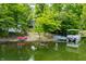 View of lakefront property with lush landscaping, a private dock, and a pontoon boat at 3695 Windsor Pl, Martinsville, IN 46151