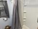 Bathroom featuring updated shower with built-in shelving, a gray shower curtain, and a toilet paper holder at 5091 Alexandria Pike, Anderson, IN 46012